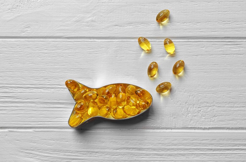 Fish oil supplement tablets arranged into the shape of a fish on a wooden surface