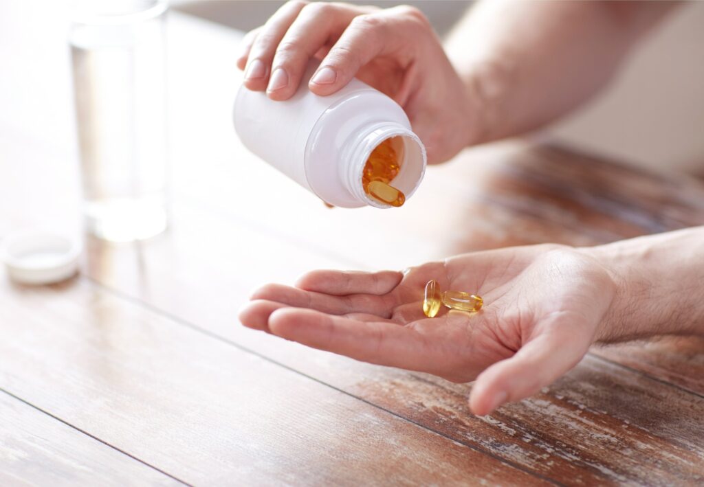 A person pouring fish oil tablets into their hand for them to take