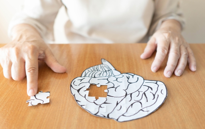 An older person removing a 'piece' of a brain-shaped puzzle