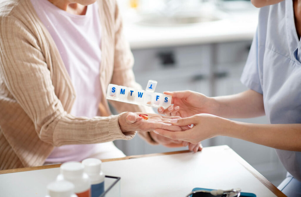 A professional caregiver at Memory Care is assisting a female patient with her medication.