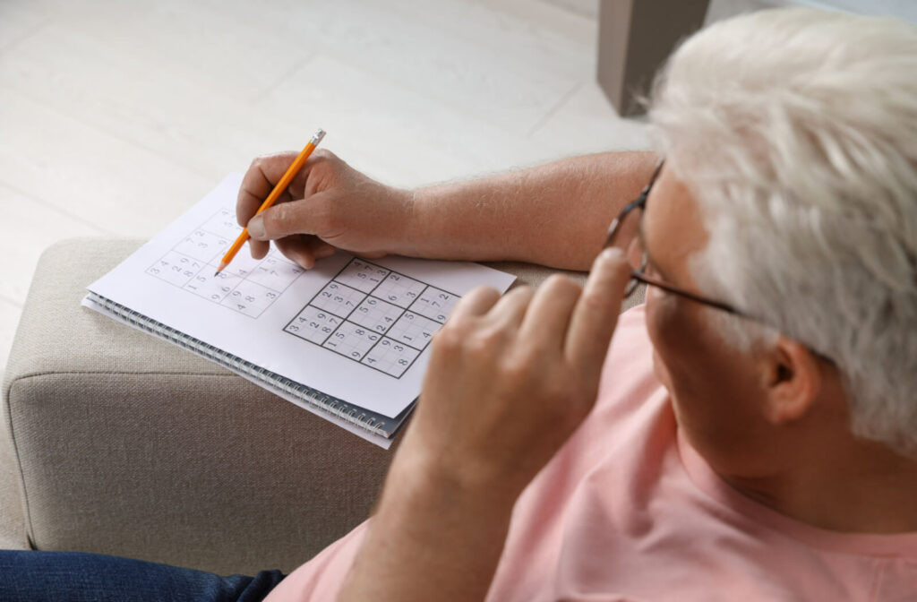 A senior person solving a Sudoku puzzle to help him improve his memory.